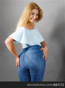Female plus size hips buttocks wearing blue jeans, woman presenting fashionable outfit. Fashion clothing femininity concept. Gray background. Woman with large hips