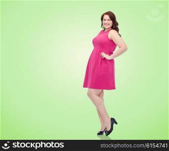female, portrait and people concept - smiling happy young plus size woman posing in pink dress over green natural background