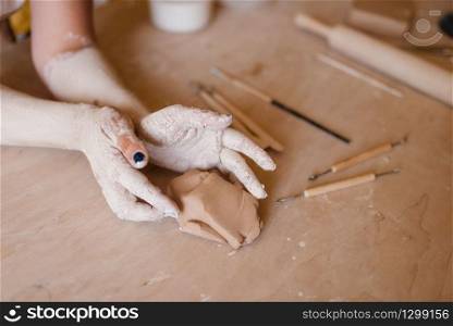 Female potter hands covered with dried clay, pottery workshop. Woman molding a bowl. Handmade ceramic art, tableware making. Female potter hands covered with dried clay