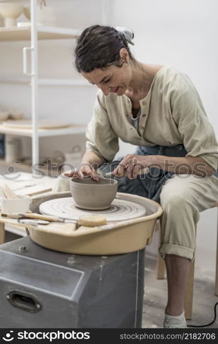 Female potter modeling clay bowl in workshop - Artisan work and creative craft concept