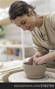 Female potter modeling clay bowl in workshop - Artisan work and creative craft concept