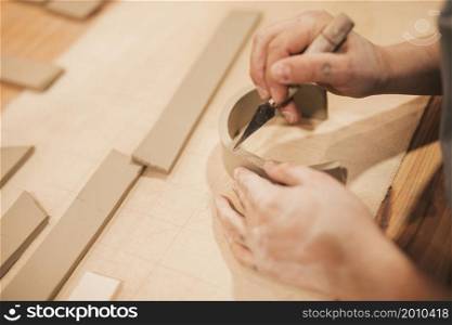 female potter s hand engraving clay with tools wooden table