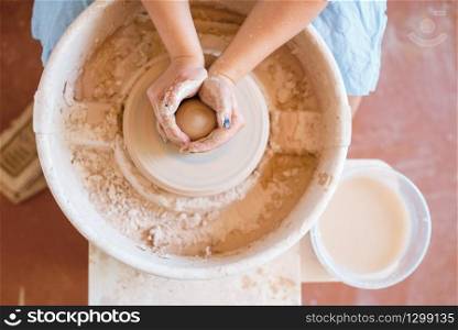 Female potter shaping a pot on pottery wheel. Woman molding a bowl. Handmade ceramic art, tableware from clay. Female potter shaping a pot on pottery wheel