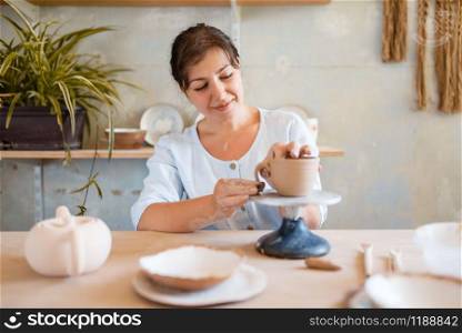 Female potter skins pot, pottery workshop. Woman molding a bowl. Handmade ceramic art, tableware from clay