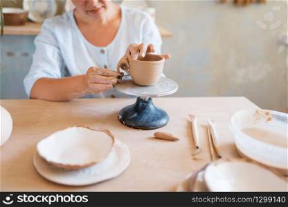 Female potter skins pot, pottery workshop. Woman molding a bowl. Handmade ceramic art, tableware from clay. Female potter skins pot, pottery workshop