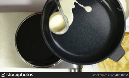 Female pouring pancake batter into the frying pan