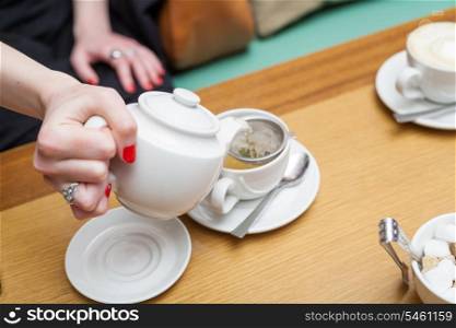 female pouring tea into the cup