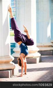 Female practice yoga doing upside down pose, outdoor, industrial city background. Physical and internal healthcare concept. Healthy lifestyle, keep fit, weight loss. Strengthen mind and body