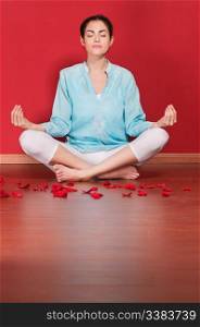 Female practicing yoga in the lotus position against colored background