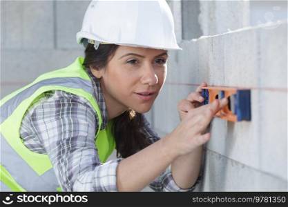 female professional builder with spirit level at site
