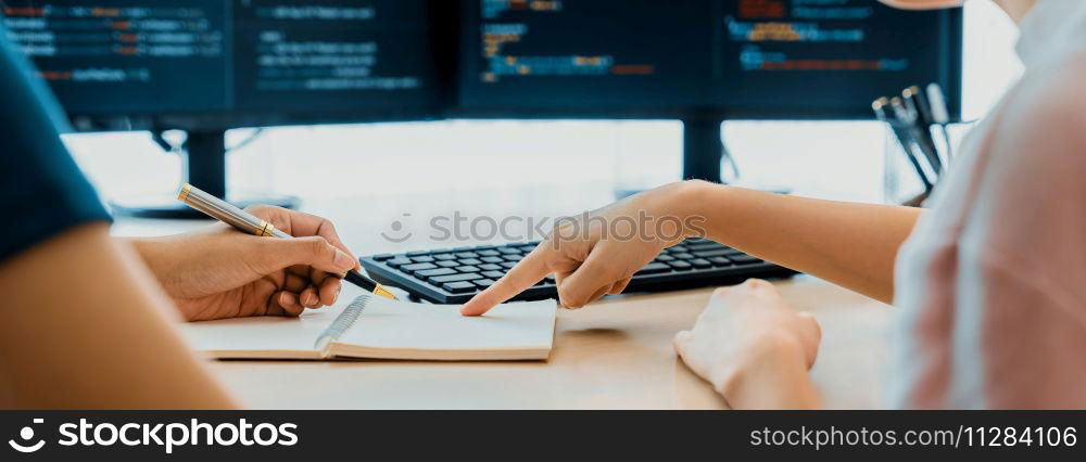 Female programer taking a note while young skilled web developer present program while computer displayed program code at modern office company. Java script, web design concept. Burgeoning.. Female programer taking a note while web developer present program. Burgeoning.