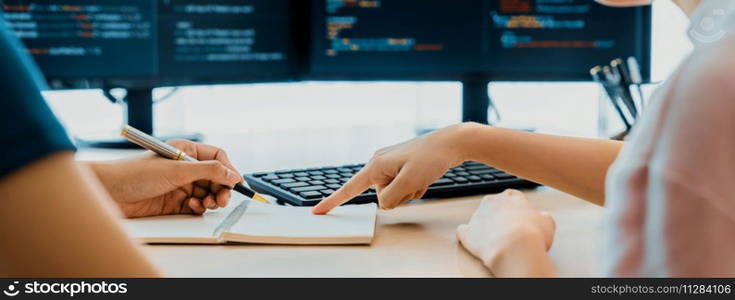 Female programer taking a note while young skilled web developer present program while computer displayed program code at modern office company. Java script, web design concept. Burgeoning.. Female programer taking a note while web developer present program. Burgeoning.