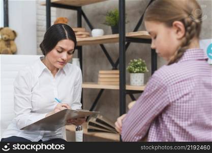 female psychologist taking notes clipboard therapy session
