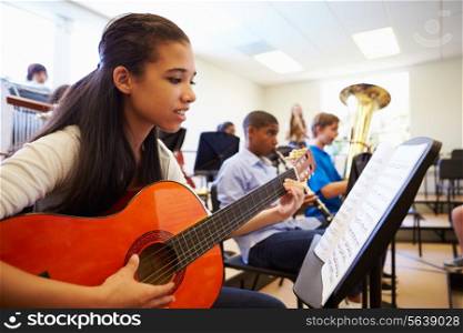 Female Pupil Playing Guitar In High School Orchestra