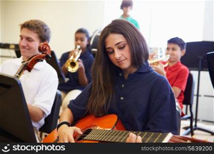 Female Pupil Playing Guitar In High School Orchestra