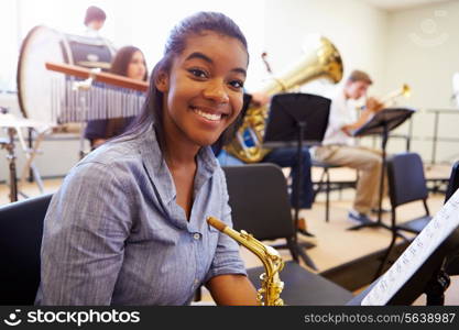 Female Pupil Playing Saxophone In High School Orchestra