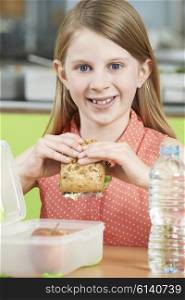 Female Pupil Sitting At Table In School Cafeteria Eating Healthy Packed Lunch
