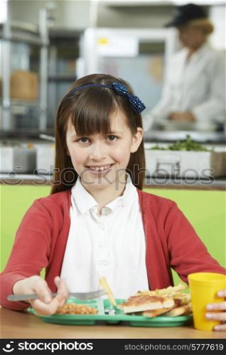 Female Pupil Sitting At Table In School Cafeteria Eating Unhealthy Lunch