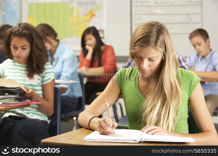Female Pupil Studying At Desk In Classroom