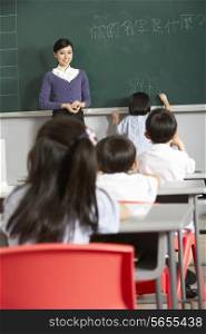 Female Pupil Writing On Blackboard In Chinese School Classroom