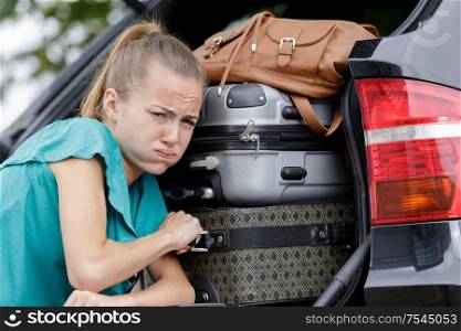 female pushing luggage in car trunk