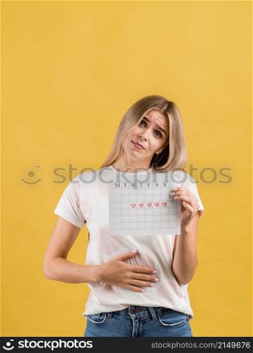 female puts hand abdomen showing period calendar
