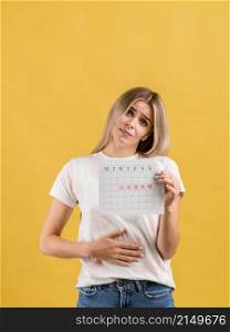 female puts hand abdomen showing period calendar