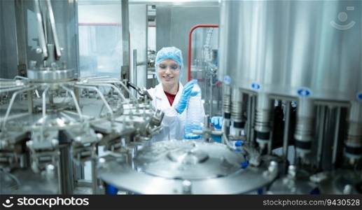 Female quality control worker inspecting water bottle on production line in drinking water factory