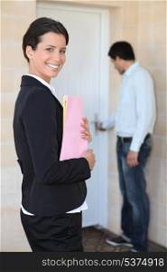 female realtor all smiles on doorstep with young client