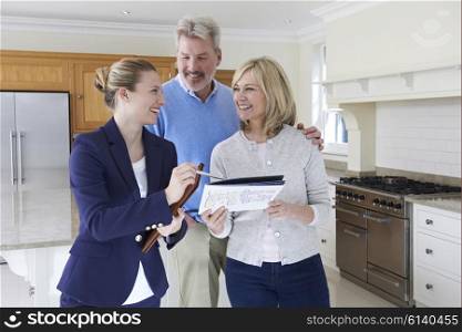 Female Realtor Showing Mature Couple Around House For Sale