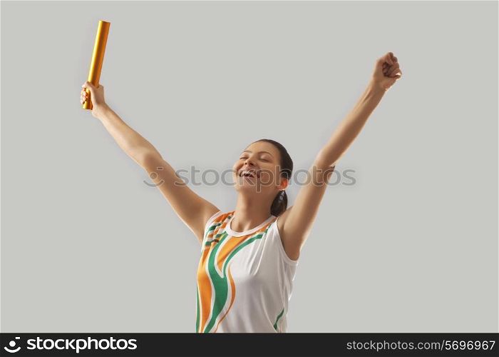 Female relay runner celebrating victory against gray background