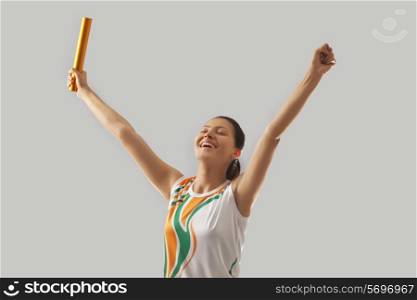 Female relay runner celebrating victory against gray background