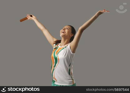 Female relay runner celebrating victory isolated over gray background