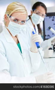 Female Research Scientist With Pipette & Flask In Laboratory