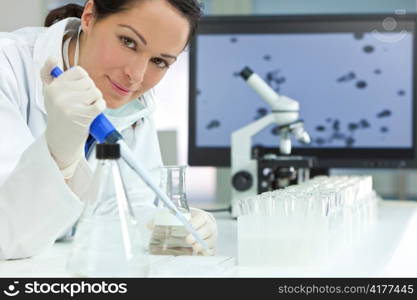 Female Research Scientist With Pipette & Flask In Laboratory