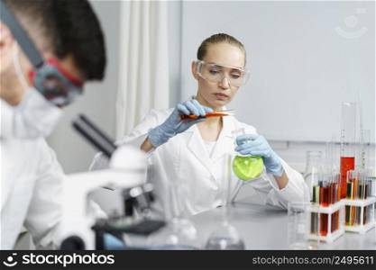 female researcher laboratory with test tubes male colleague