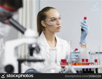 female researcher laboratory with test tubes safety glasses male colleague
