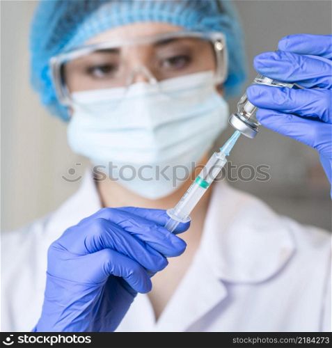 female researcher with safety glasses medical mask holding syringe
