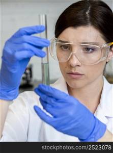 female researcher with test tube safety glasses
