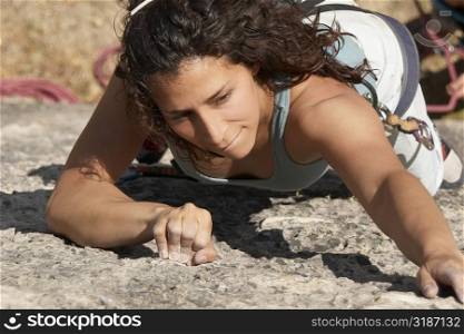 Female rock climber scaling a rock face