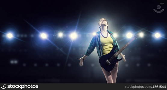 Female rock guitarist. Young attractive rock girl with electric guitar on stage