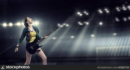 Female rock guitarist. Young attractive rock girl with electric guitar on stage