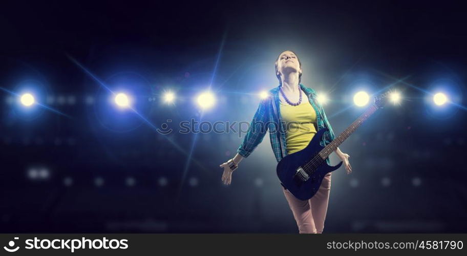 Female rock guitarist. Young attractive rock girl with electric guitar on stage