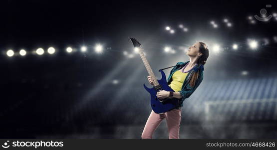 Female rock guitarist. Young attractive rock girl with electric guitar on stage