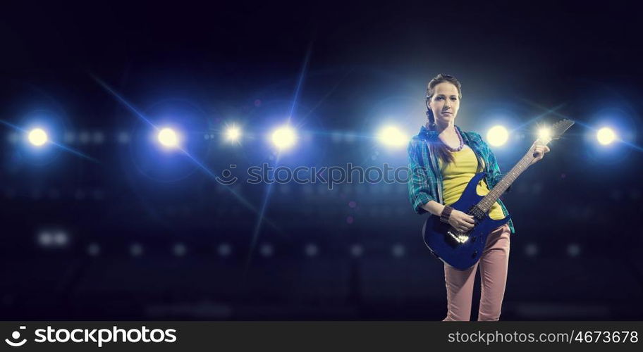 Female rock guitarist. Young attractive rock girl with electric guitar on stage