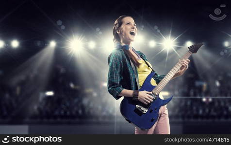 Female rock guitarist. Young attractive rock girl with electric guitar on stage