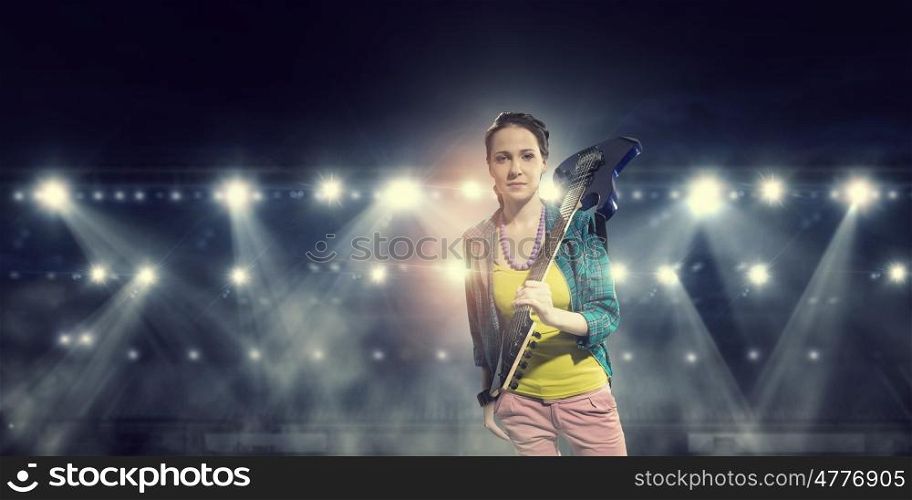 Female rock guitarist. Young attractive rock girl with electric guitar on stage