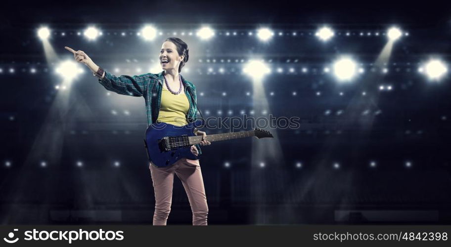 Female rock guitarist. Young attractive rock girl with electric guitar on stage