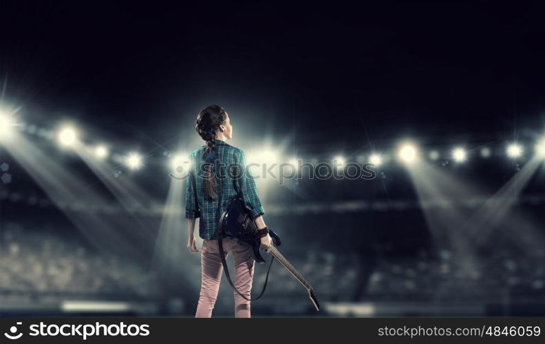 Female rock guitarist. Young attractive rock girl with electric guitar on stage