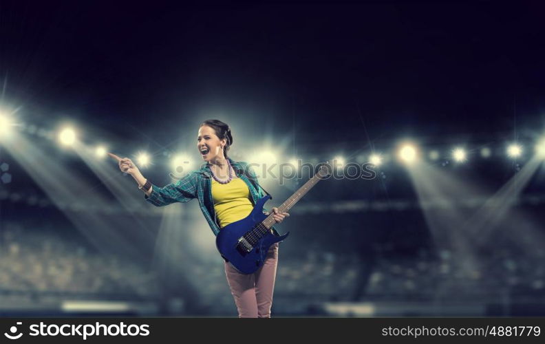 Female rock guitarist. Young attractive rock girl with electric guitar on stage